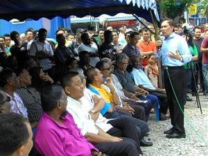 ANWAR Ibrahim (berdiri, memegang mikrofon) ketika memberi taklimat bersempena program Kembara Tawan 416: DSAI Bersama Rakyat di perkarangan Tapak Penjaja Sementara Bukit Gedung di sini baru-baru ini. 