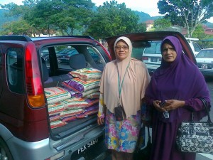 ASNAH Hashim (kiri) bersama pembantunya bersedia untuk mengagihkan beras kepada 10 buah keluarga terpilih di Teluk Kumbar di sini baru-baru ini.