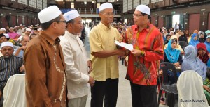 MOHD. Salleh Man (berdiri, kanan sekali) sambil ditemani, Dr. Elias Zakaria (berdiri, dua dari kiri) menyampaikan sumbangan saguhati zakat kepada salah seorang penerima pada majlis penyampaian di sini baru-baru ini.