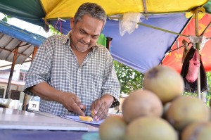 PAK Mad memotong buah ciku jualannya untuk dirasai pelanggan. 